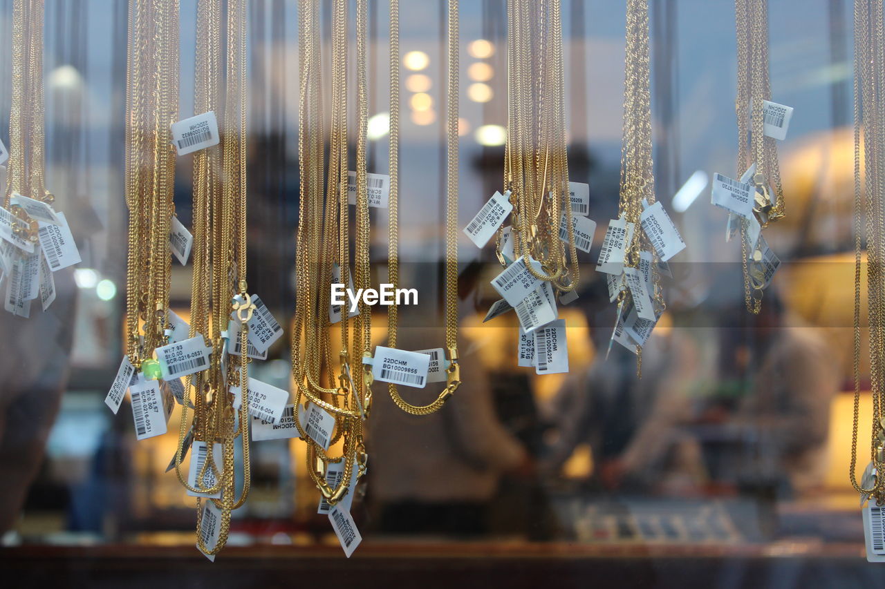 Close-up of necklace hanging at store seen through glass