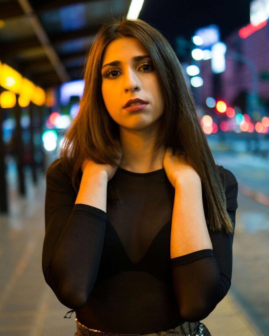 Portrait of young woman standing on city street at night