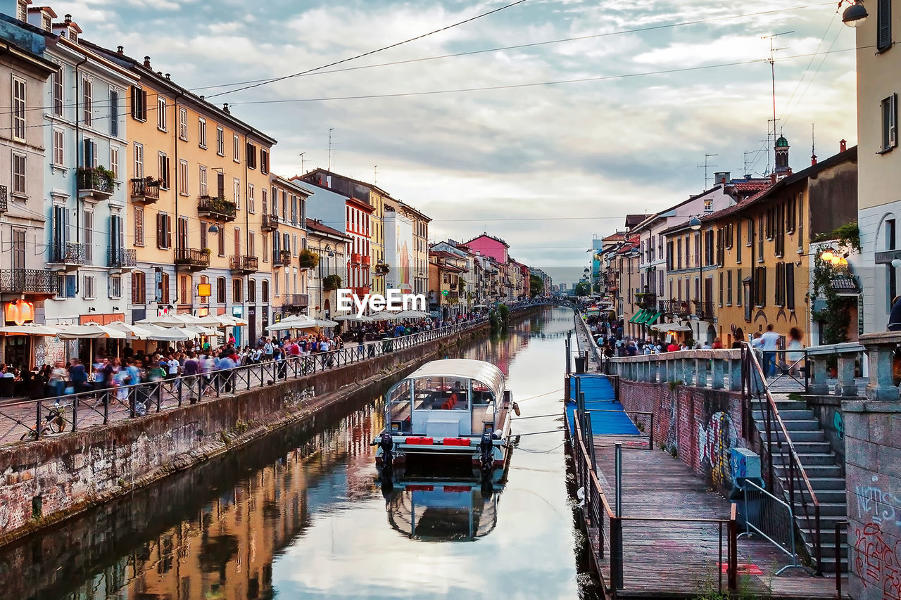 Buildings amidst canal at naviglio grande against sky