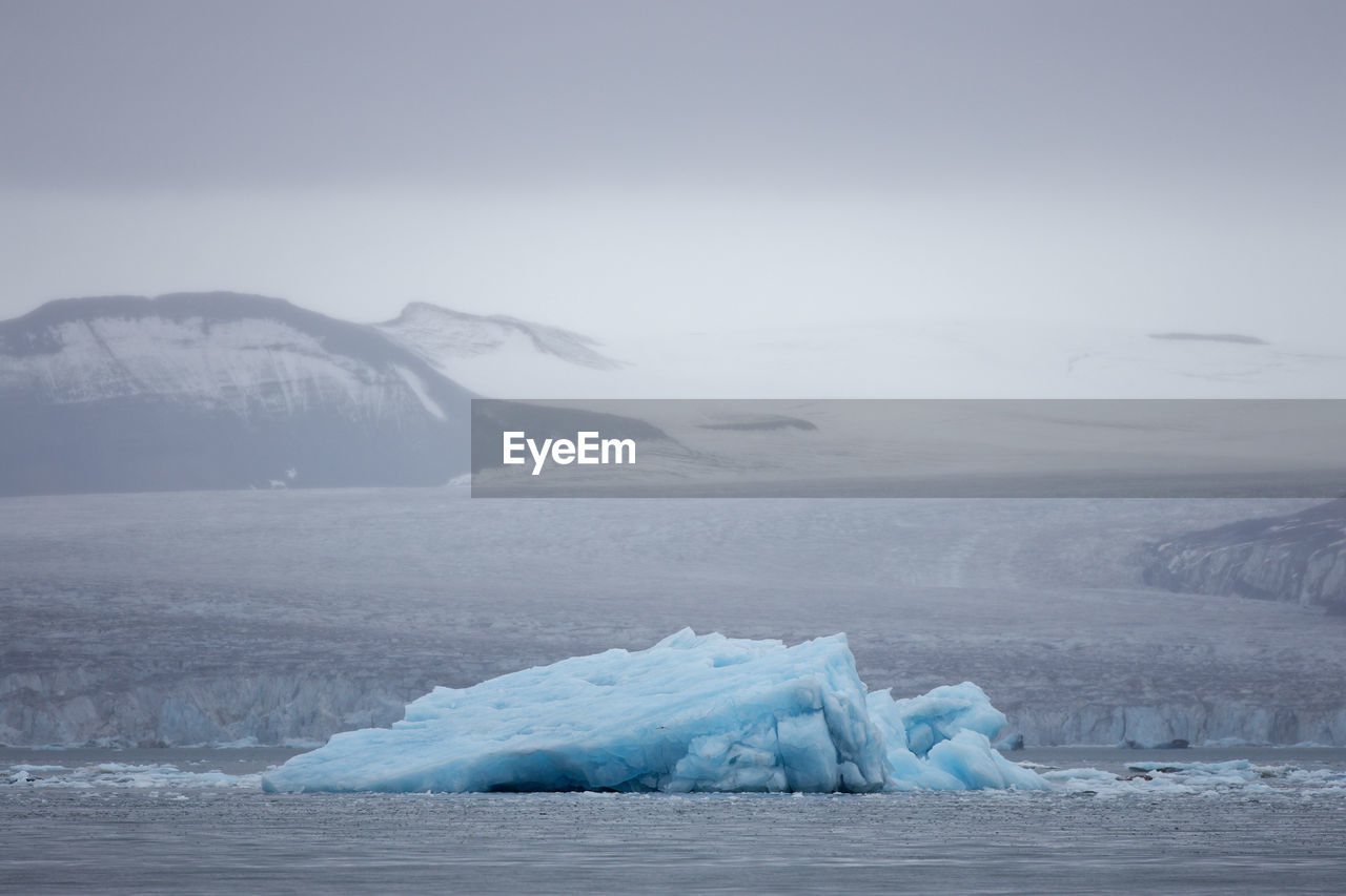 Blue ice iceberg in front of a glacier at svalbard