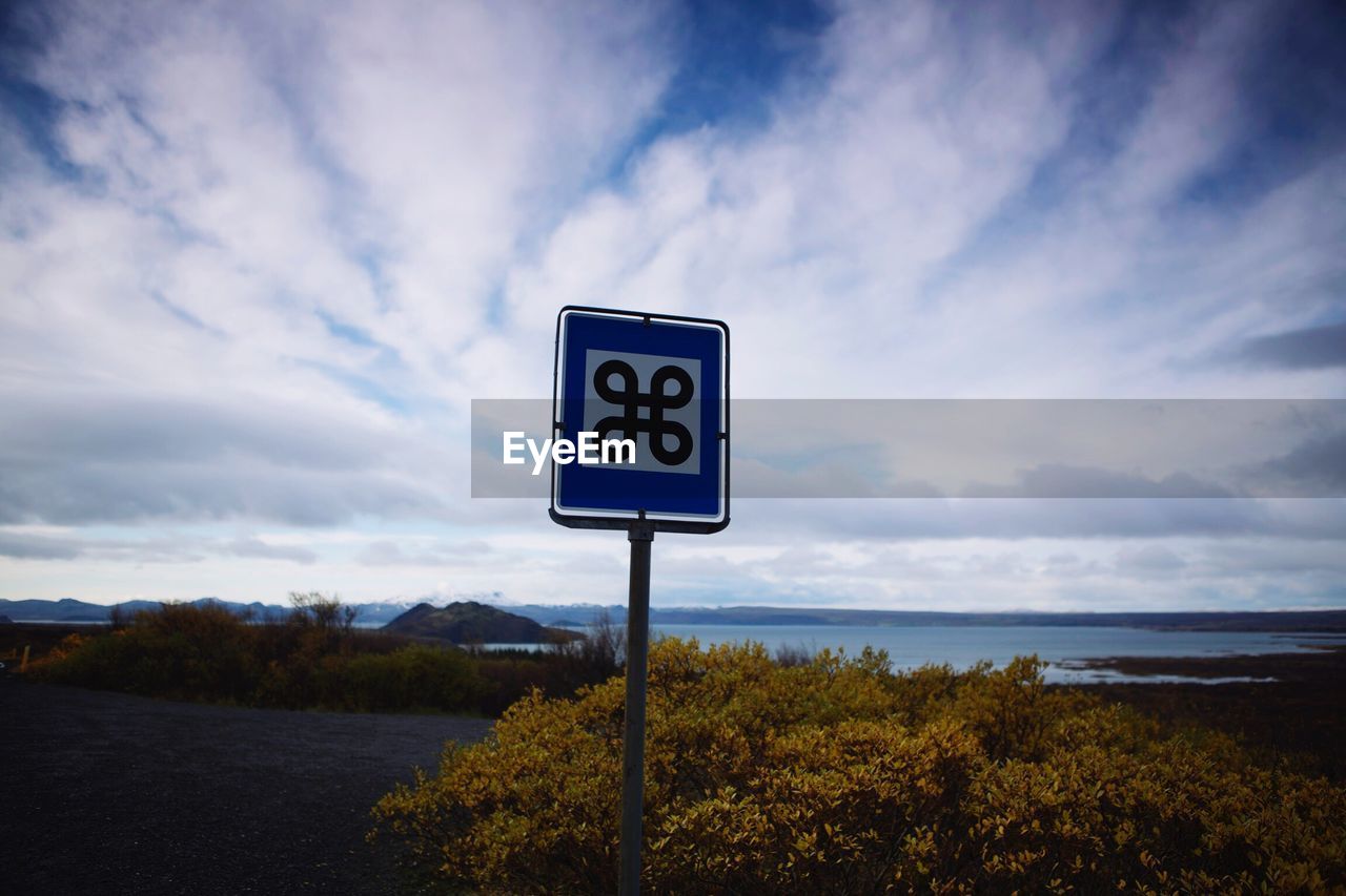 Low angle view of road sign against cloudy sky