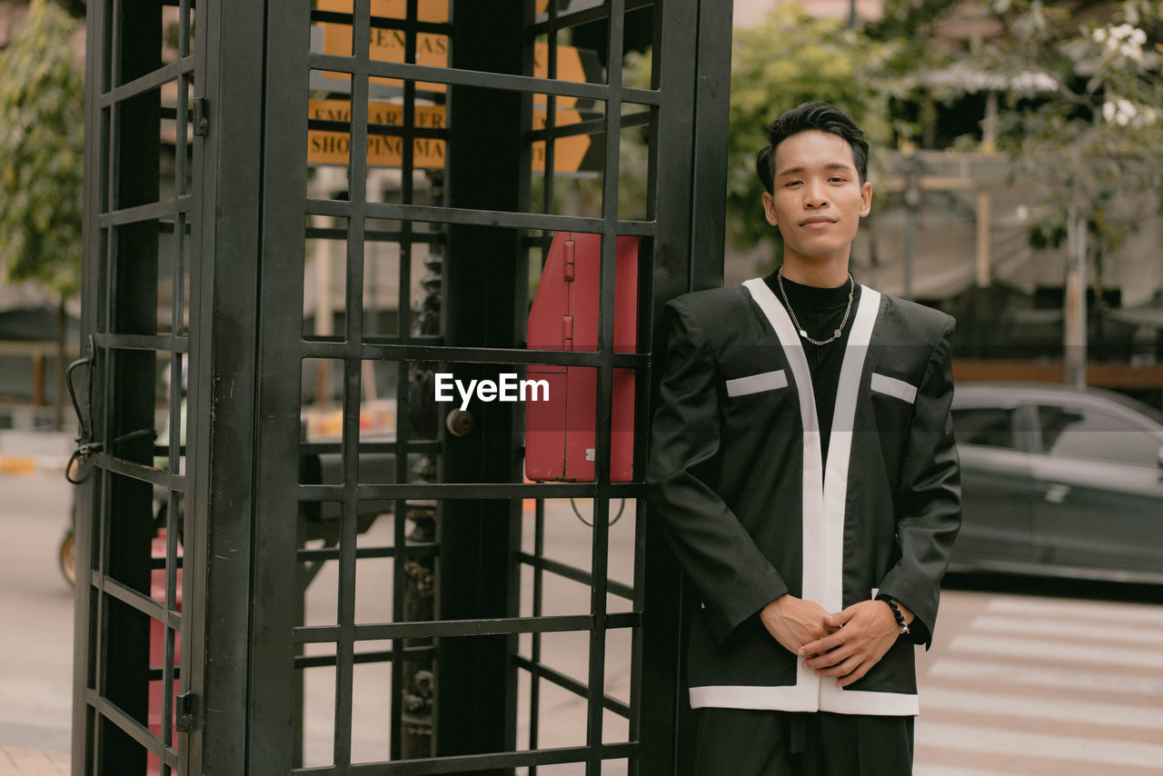 one person, adult, men, business, portrait, architecture, looking at camera, standing, businessman, front view, occupation, smiling, business finance and industry, building, clothing, emotion, person, three quarter length, city, formal wear, building exterior, corporate business, happiness, spring