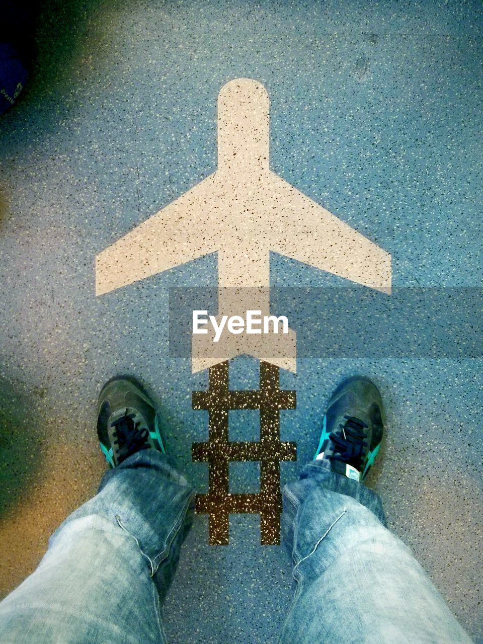 Low section of man standing at airport with airplane drawing on floor