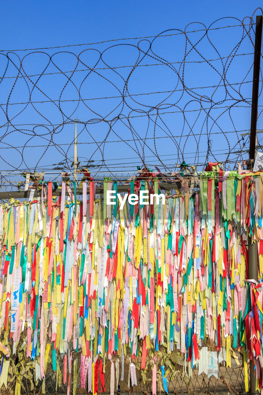 MULTI COLORED UMBRELLAS HANGING AGAINST CLEAR SKY