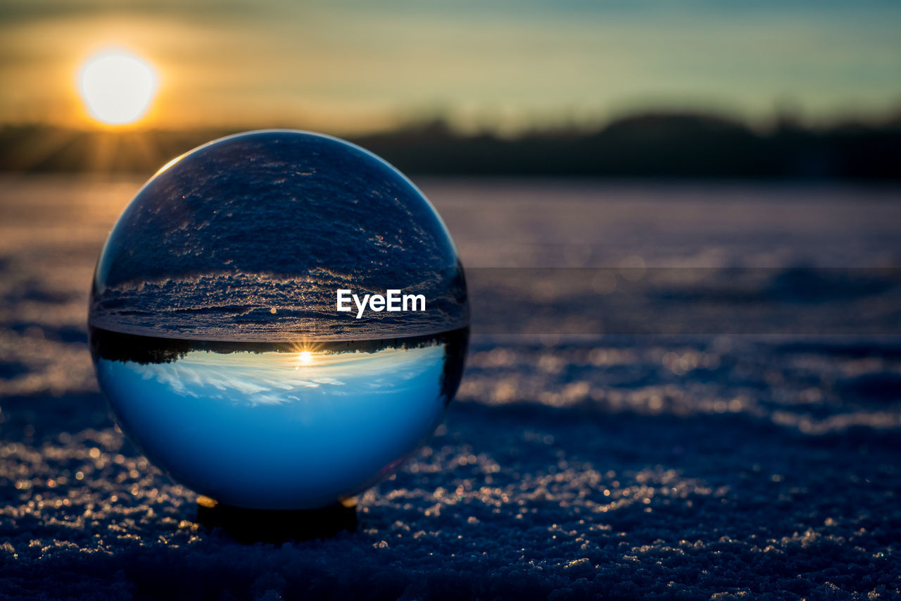 CLOSE-UP OF CRYSTAL BALL ON SHORE