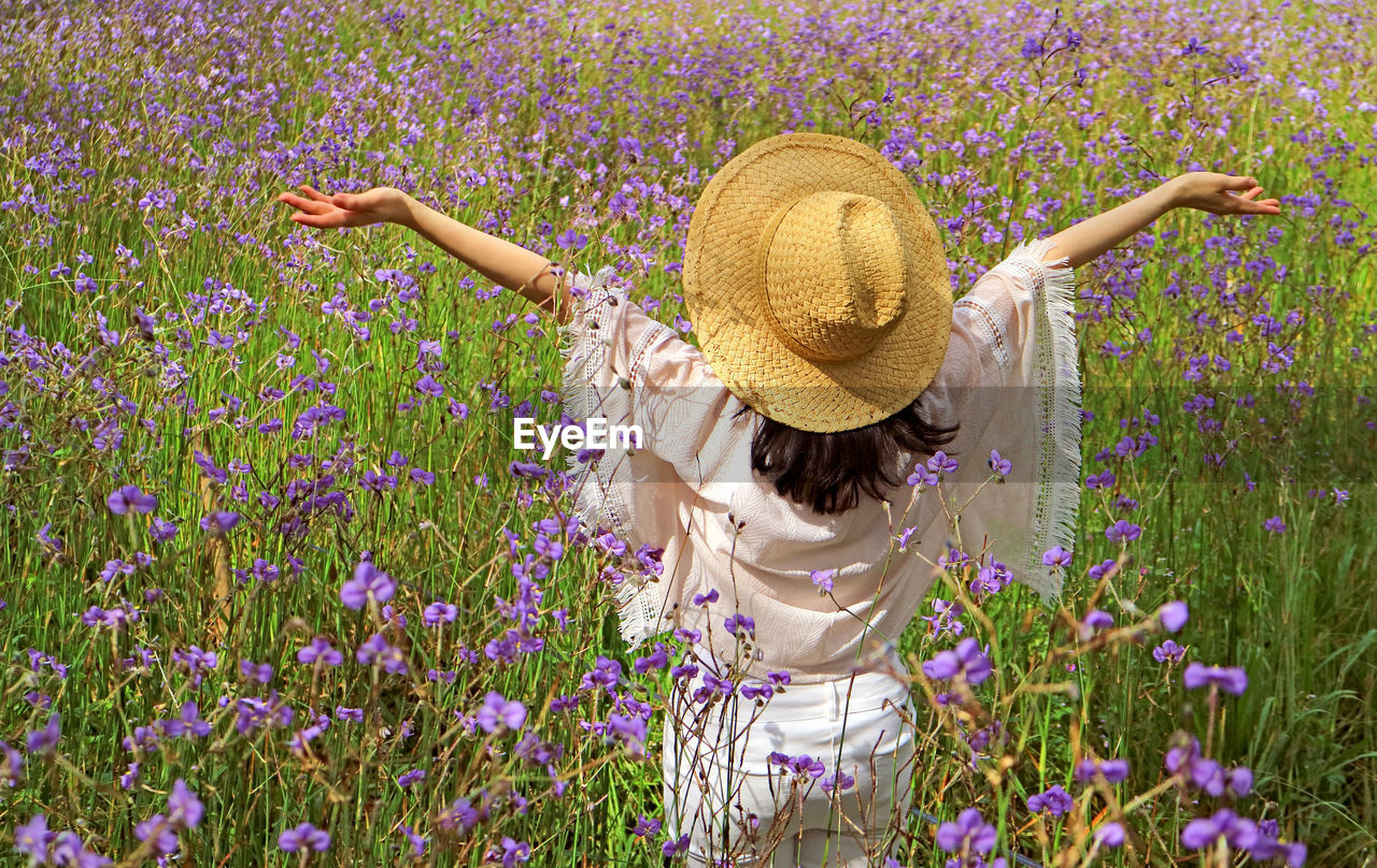 Rear view of woman standing by purple flowers on land