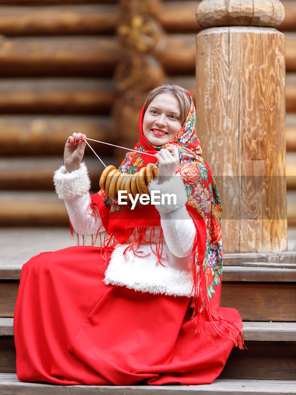 one person, smiling, women, clothing, happiness, adult, traditional clothing, red, architecture, portrait, person, tradition, female, cheerful, sitting, lifestyles, emotion, looking at camera, holding, celebration, young adult, full length, child, childhood, staircase, outdoors, religion, temple - building, event, holiday, human face, history