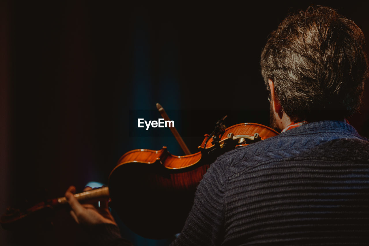 Rear view of man playing violin