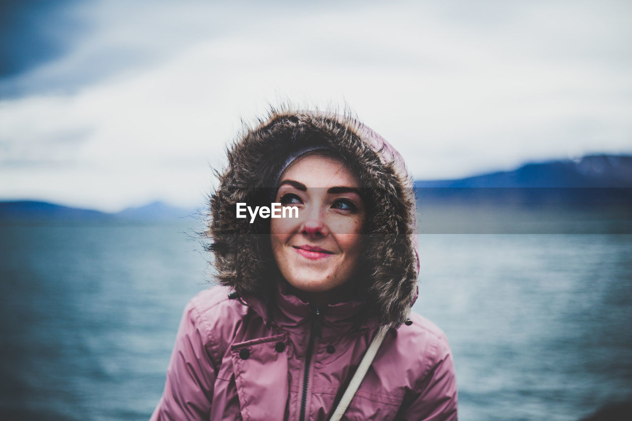 Smiling woman in warm clothes against sea 