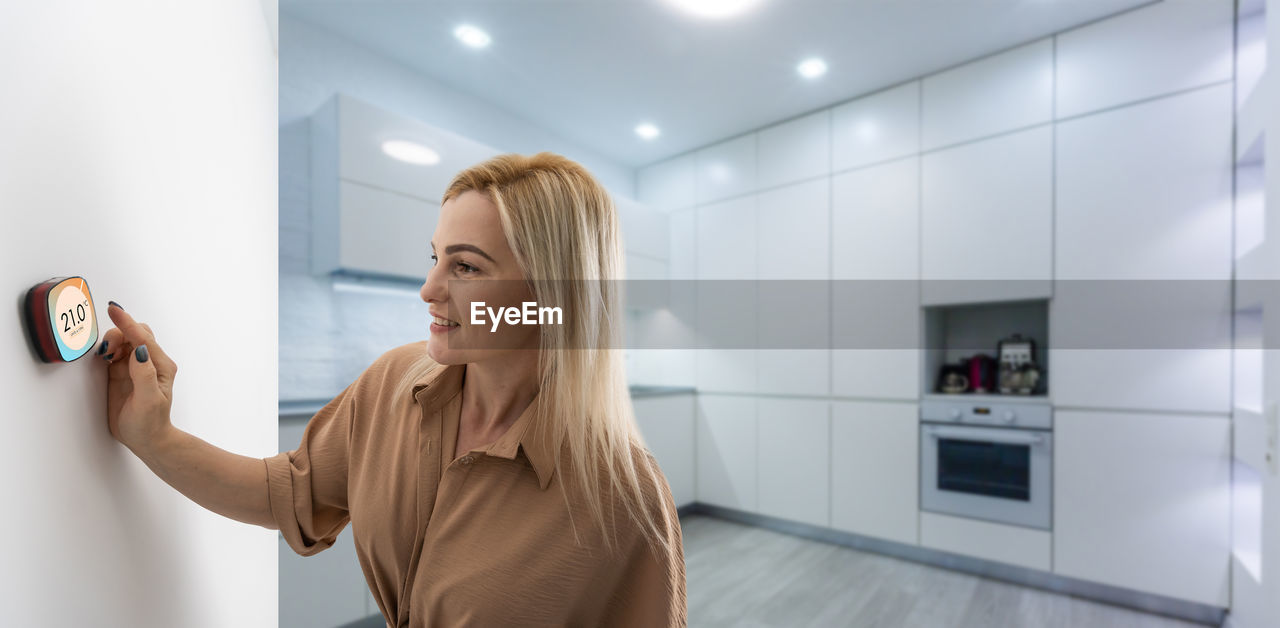 Woman using smartphone monitor to control home connectivity interface