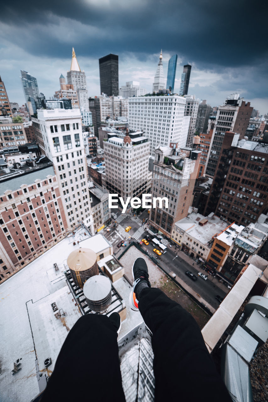 Low section of man and cityscape against sky