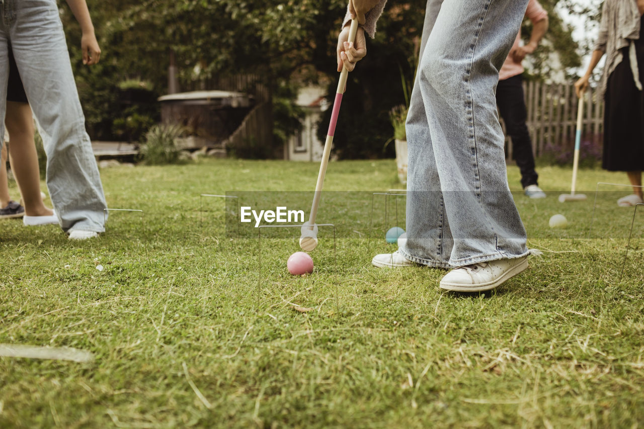 Low section of teenage girl playing polo with family in front yard