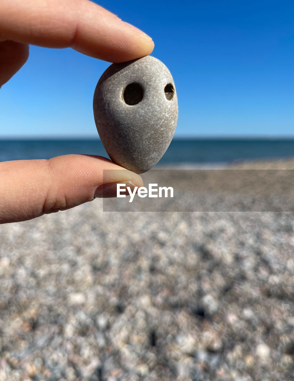 CLOSE-UP OF PERSON HAND HOLDING SEA AGAINST SKY