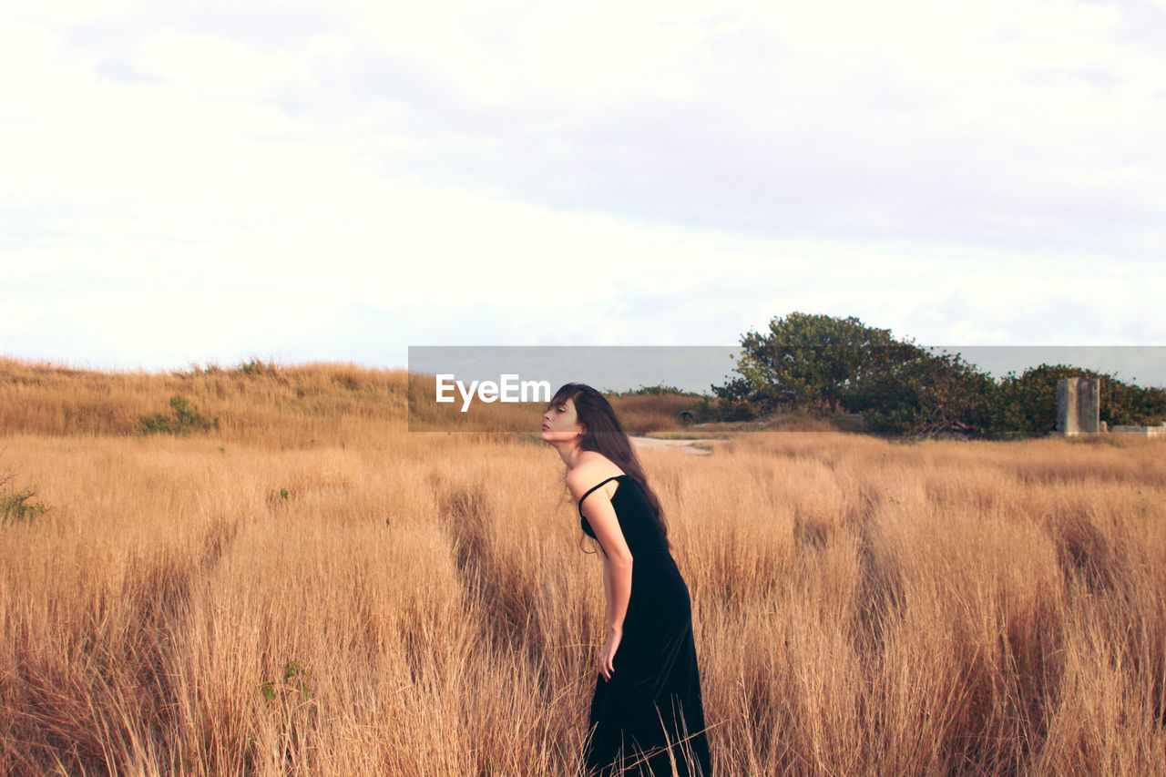 Rear view of woman standing on field against sky