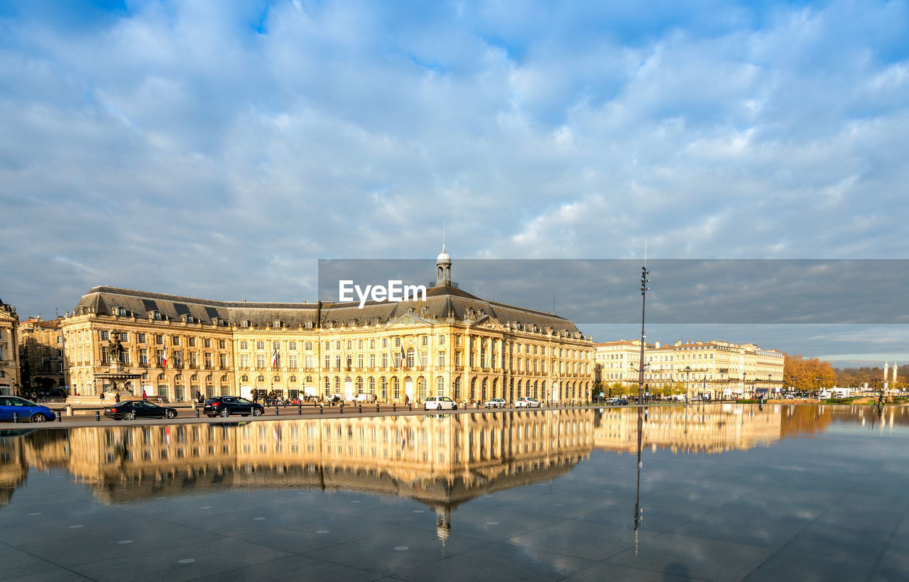 Reflection of building in lake water against cloudy sky