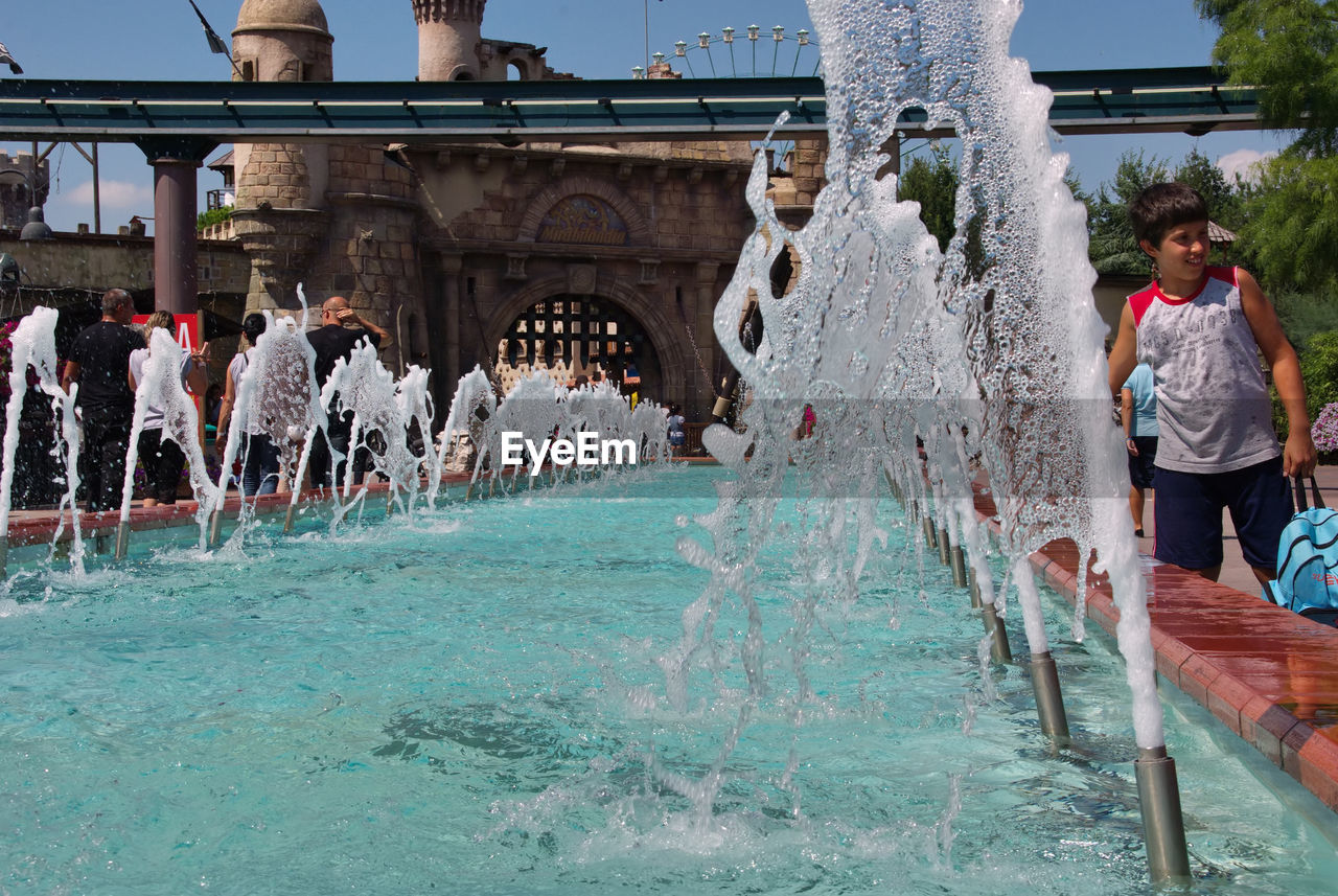 PEOPLE IN SWIMMING POOL AGAINST BUILT STRUCTURE