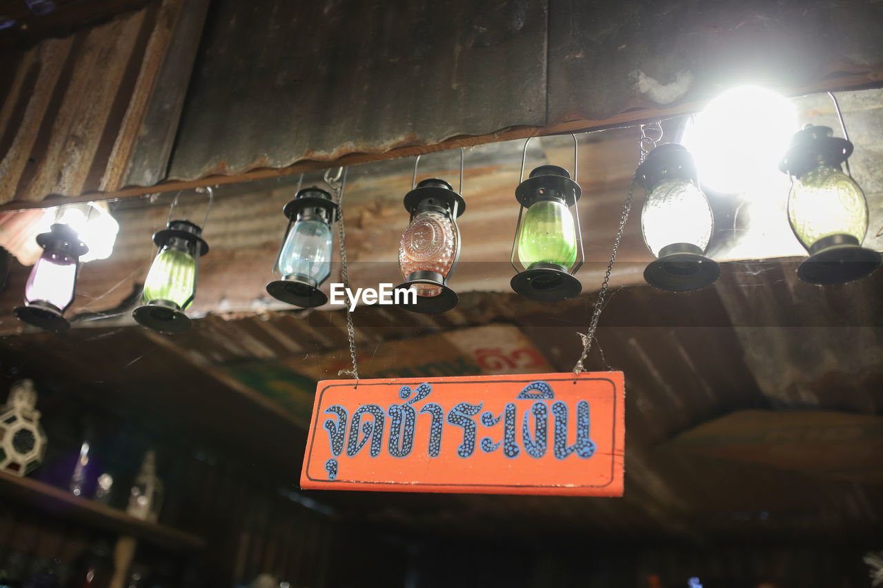 LOW ANGLE VIEW OF ILLUMINATED LIGHTING EQUIPMENT HANGING ON WALL