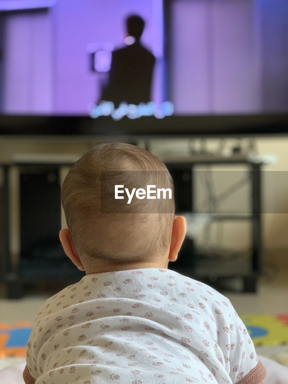 Rear view of baby boy watching tv at home