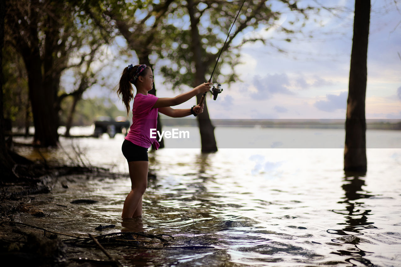 Side view of girl fishing in lake