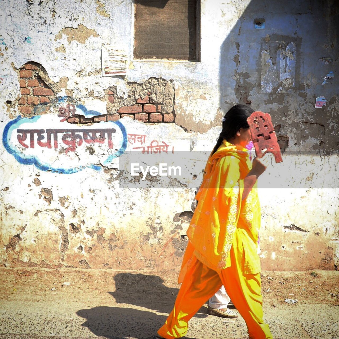 Women walking on street by damaged wall
