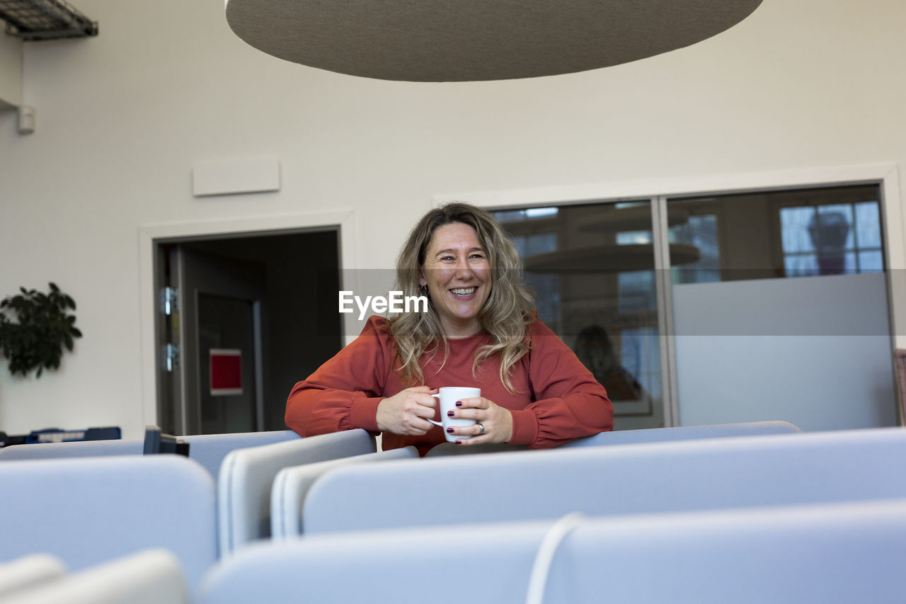 Smiling woman holding mug in office