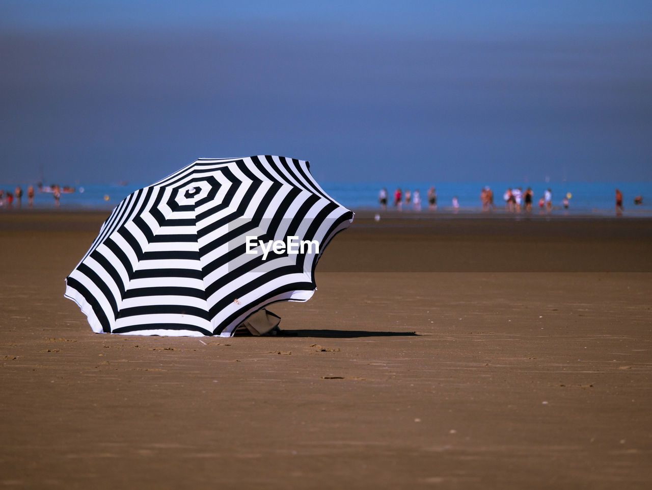 Striped parasol at beach against sky