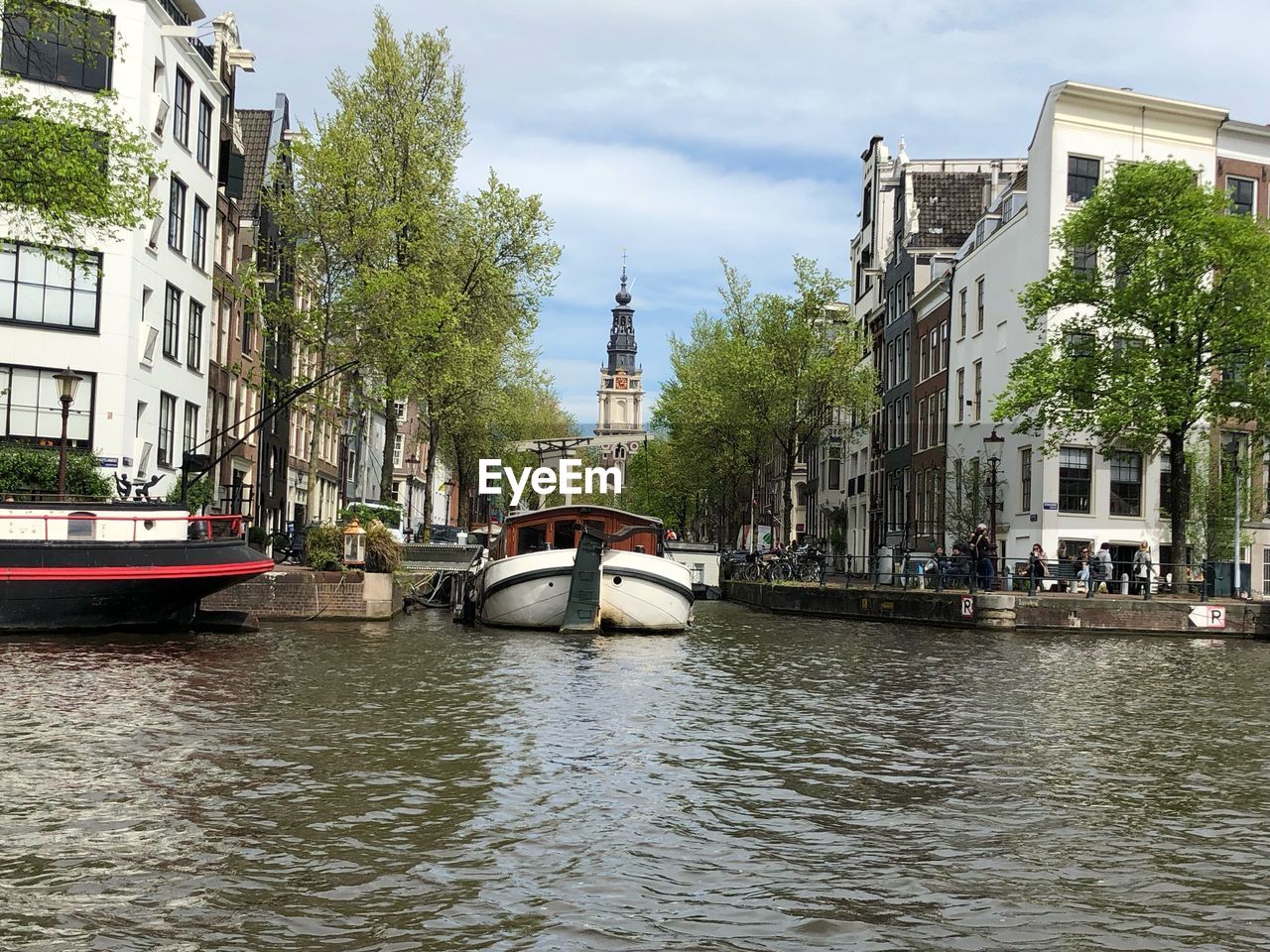 BOATS IN CANAL BY BUILDINGS AGAINST SKY