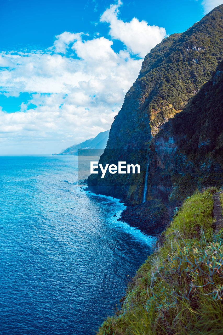 Scenic view of sea and mountains against blue sky