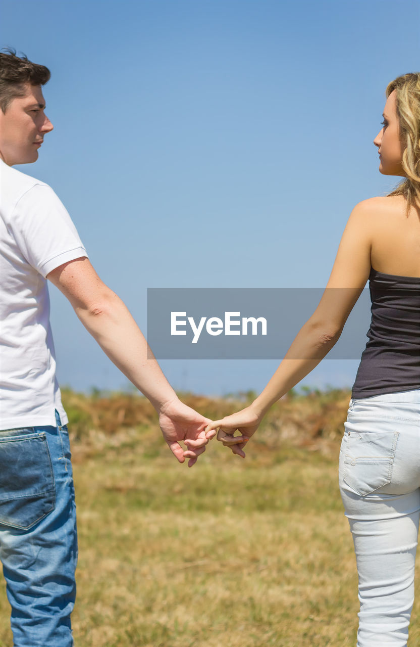 MIDSECTION OF COUPLE STANDING ON LAND