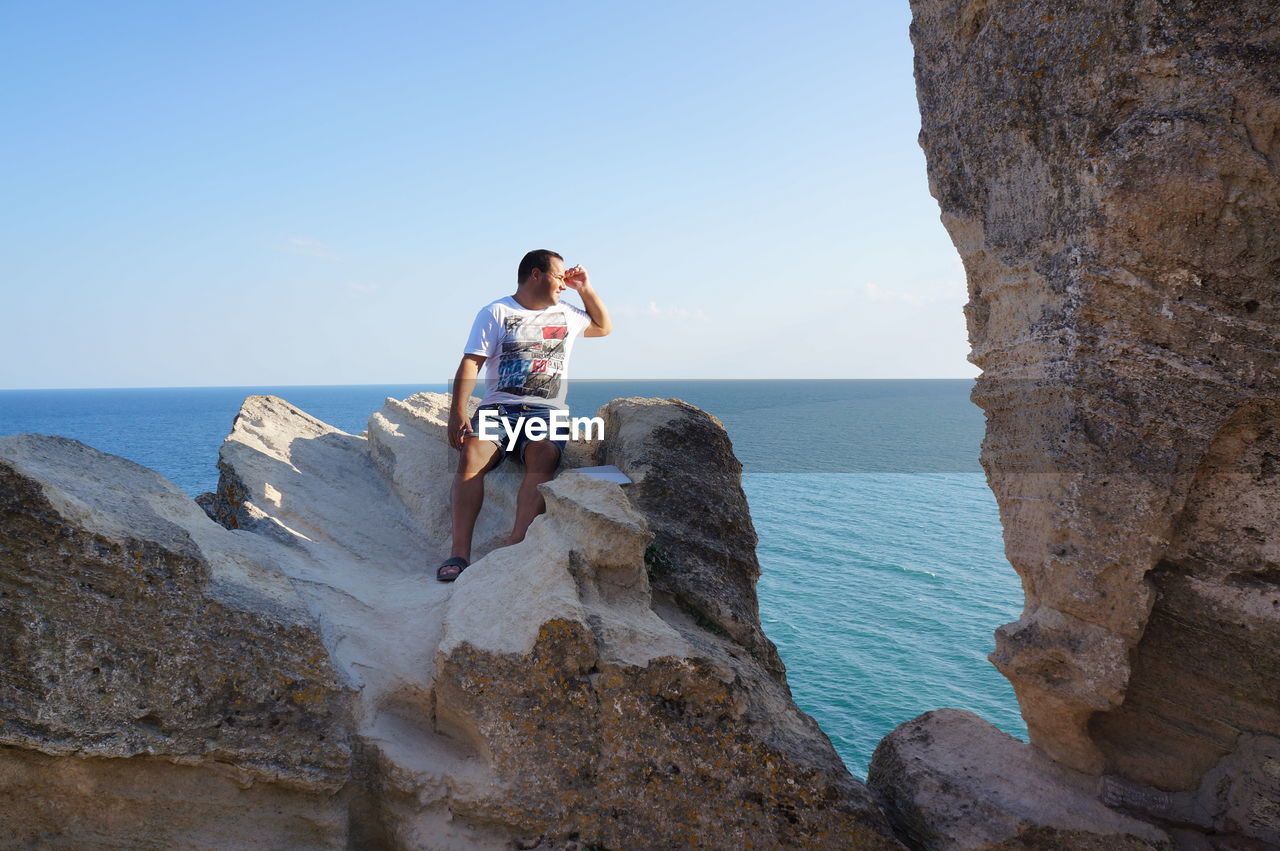 Man sitting on rock against sea