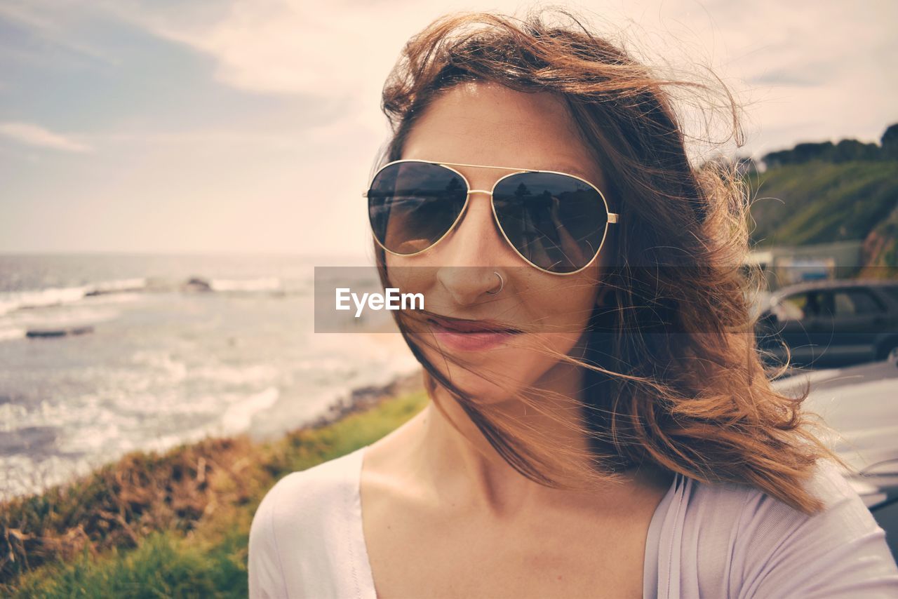 Portrait of woman wearing sunglasses against sea