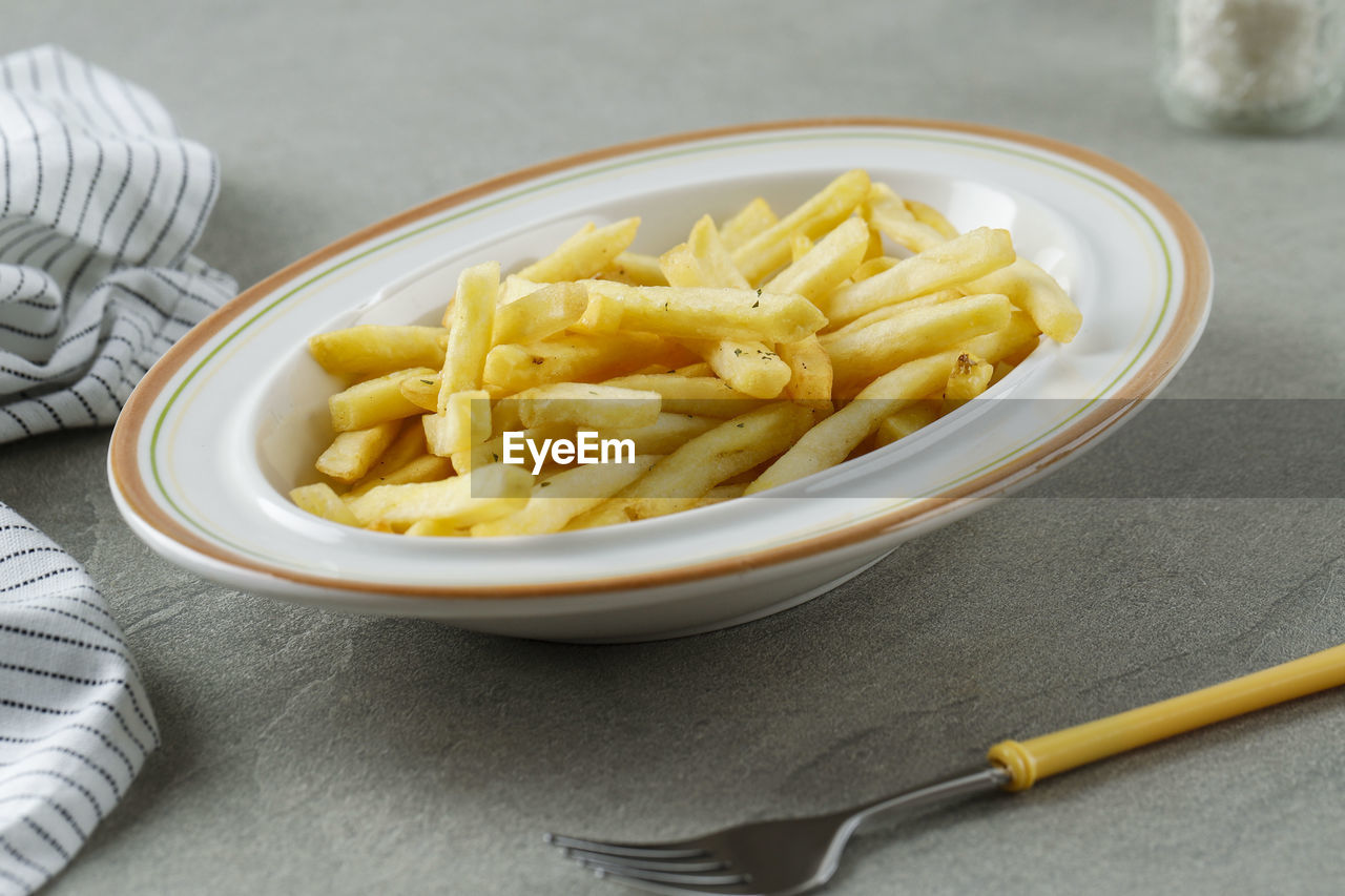 Portion of french fries on white plate, close up . concept fast food