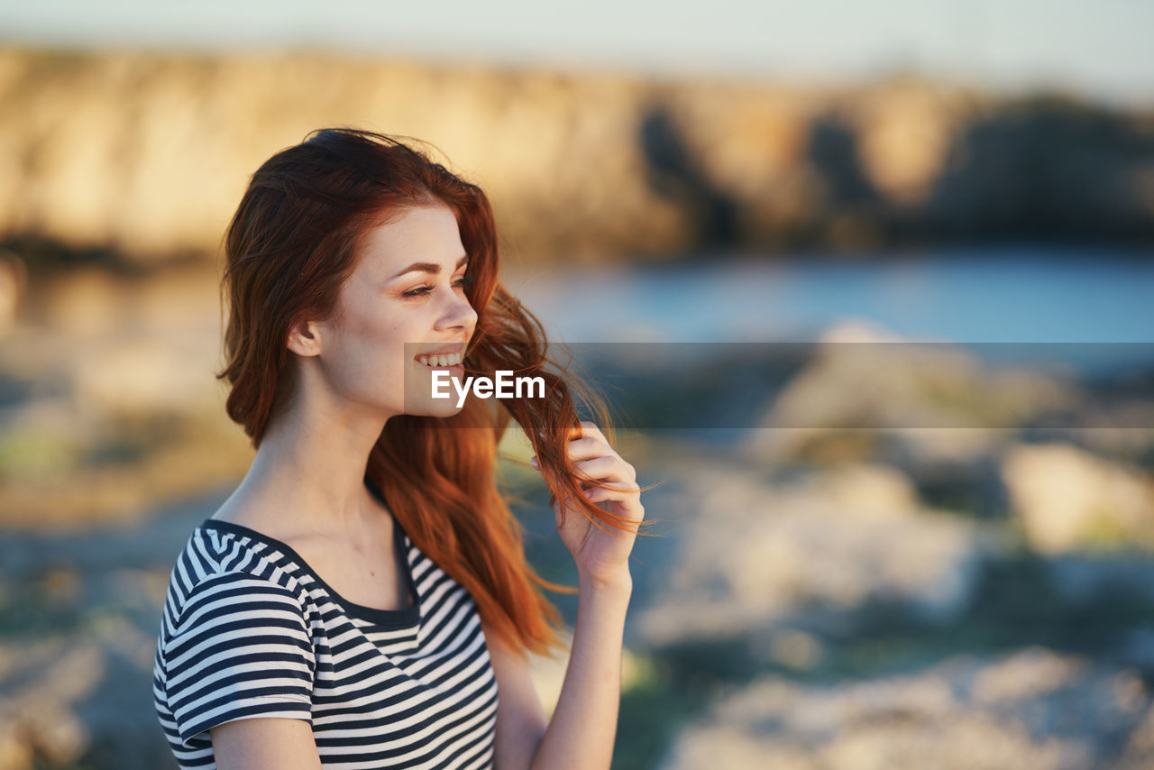 Beautiful young woman looking at sea shore