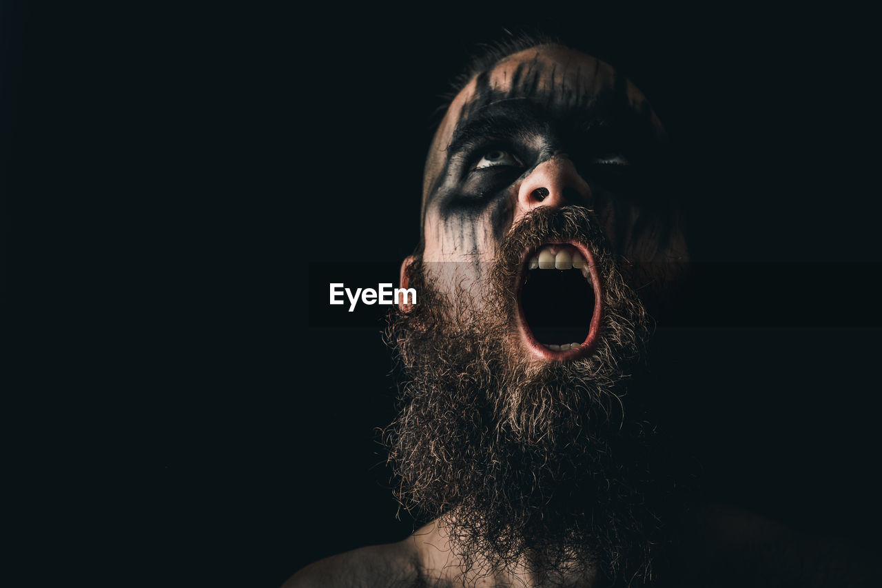 Portrait of a viking warrior with black war paint, screaming with rage and anger