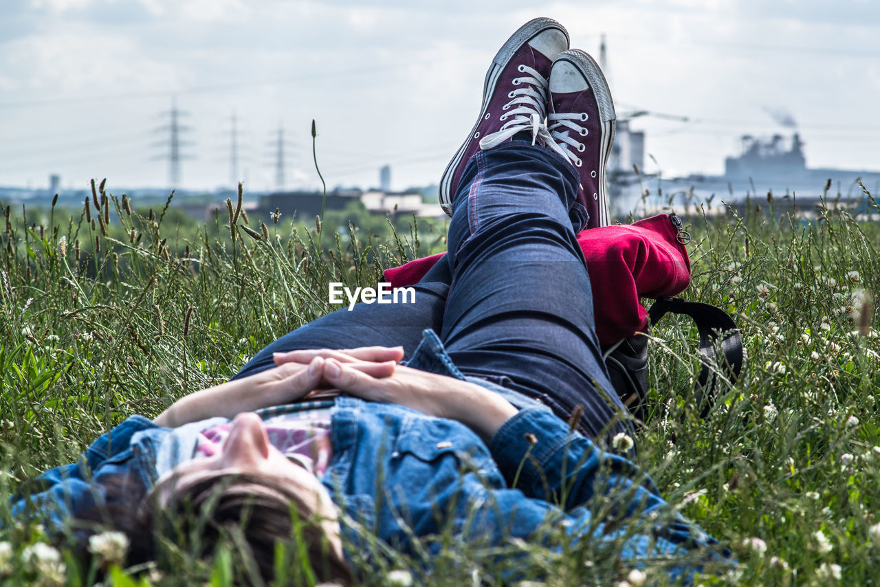 MIDSECTION OF WOMAN SITTING ON FIELD IN GARDEN