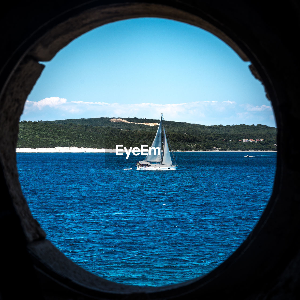 Sailboat sailing in sea seen through window against sky