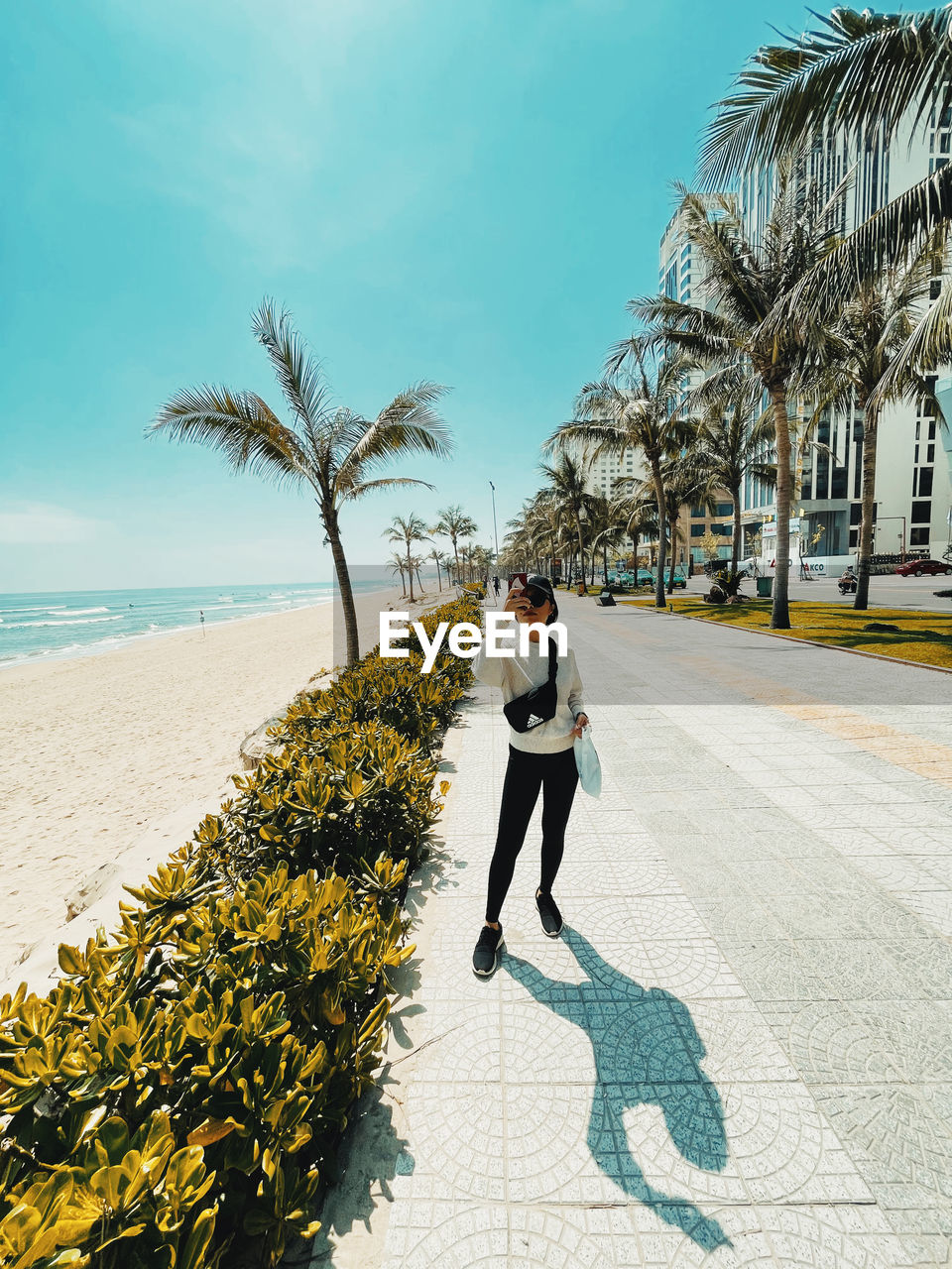 FULL LENGTH OF YOUNG WOMAN ON PALM TREE