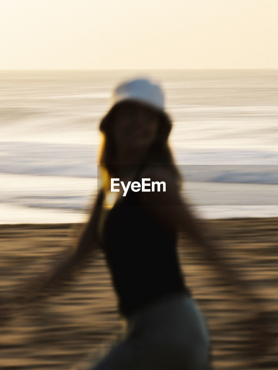 Rear view of woman running at beach against sky