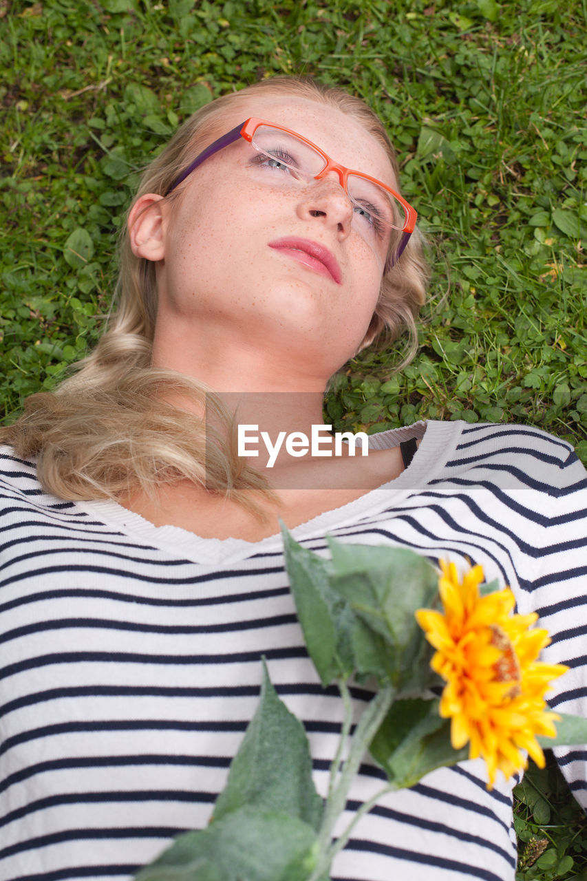 High angle view of young woman with flower lying on grassy field at park