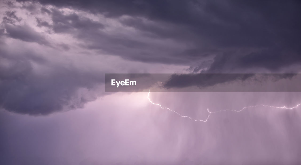 Low angle view of sunlight streaming through clouds