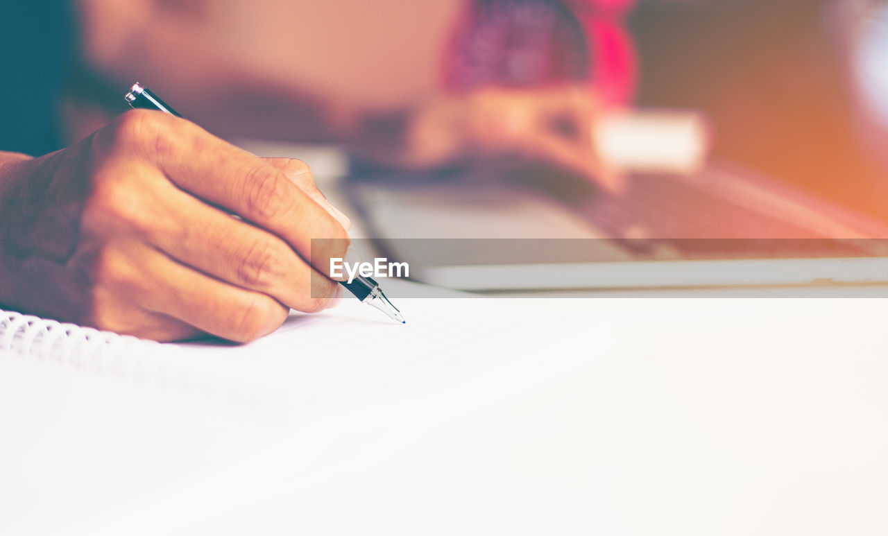 MIDSECTION OF MAN HOLDING PAPER WITH TEXT