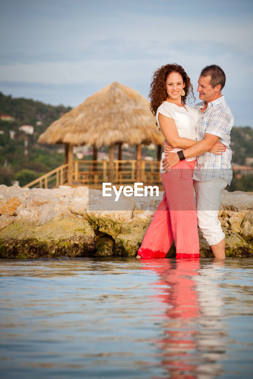 Mature couple dancing in sea against sky