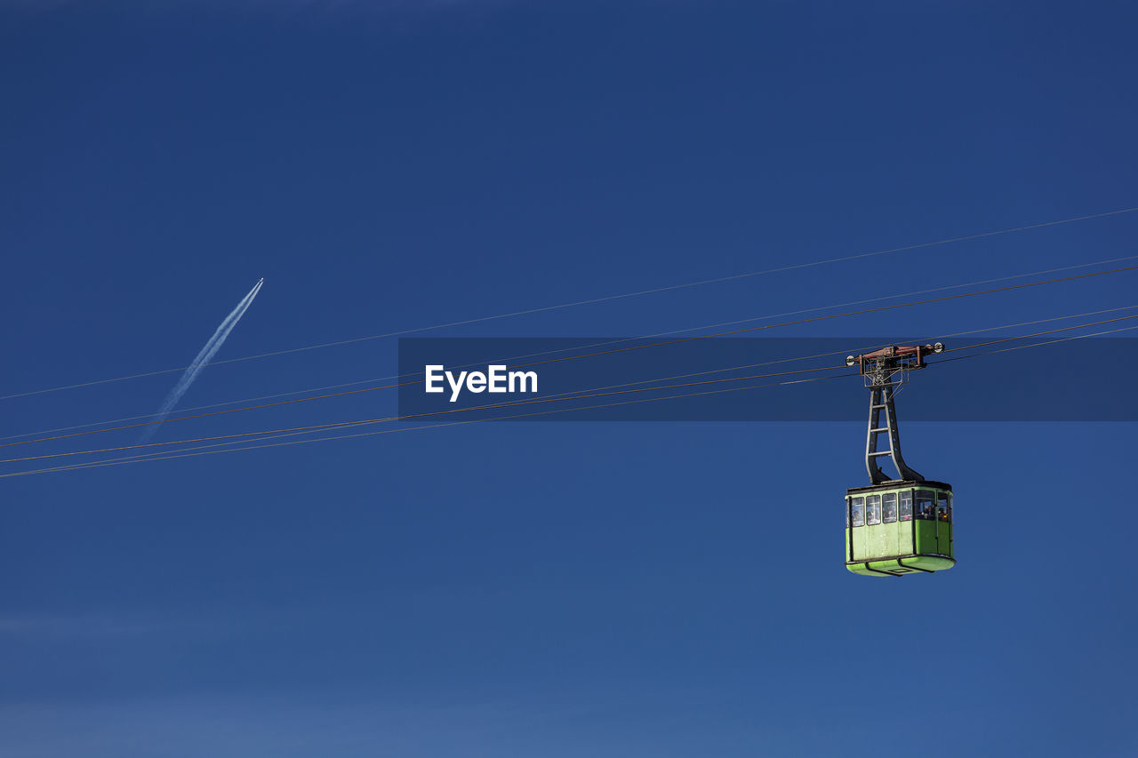 LOW ANGLE VIEW OF OVERHEAD CABLE CARS AGAINST BLUE SKY