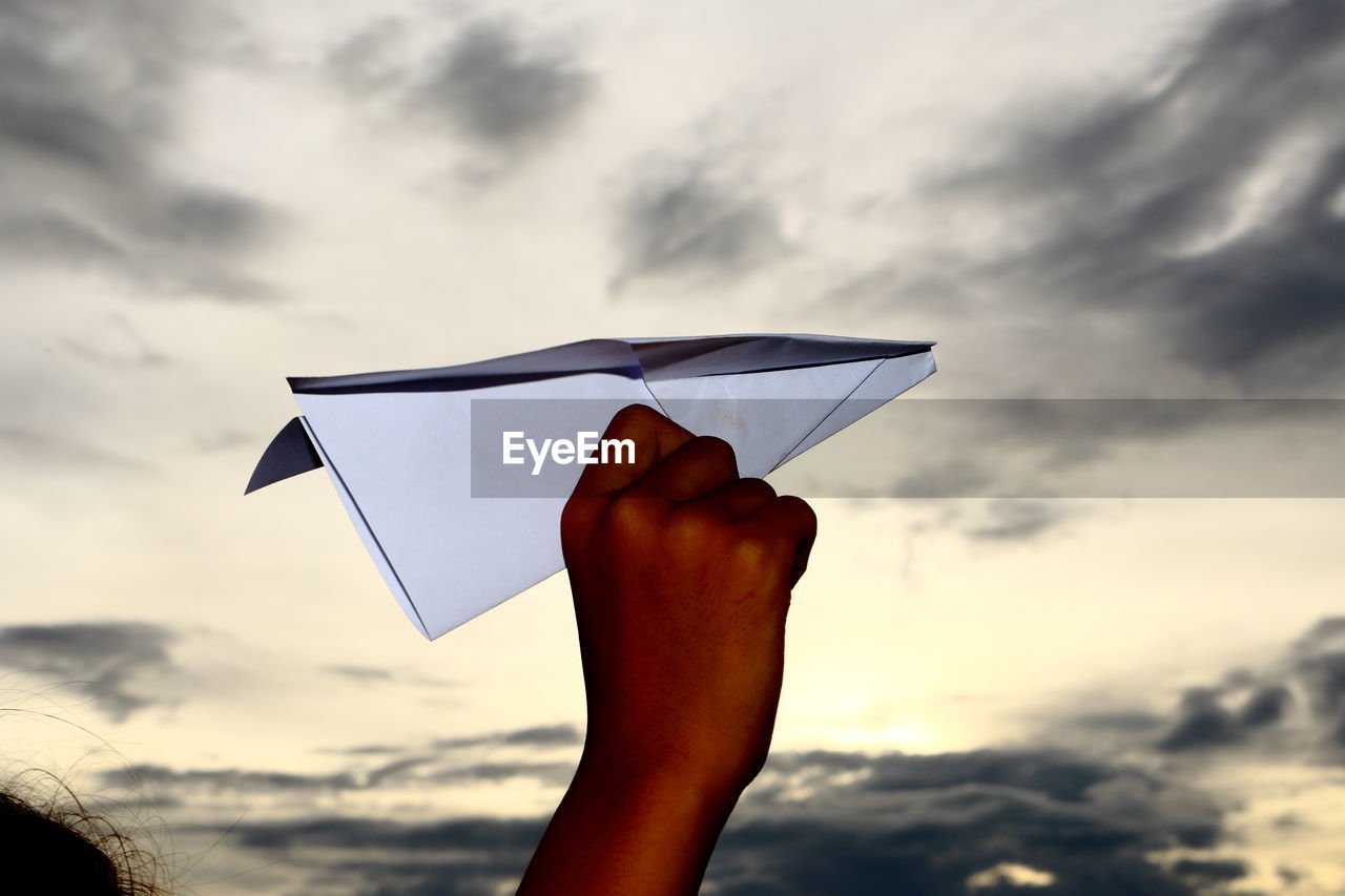 CLOSE-UP OF HAND HOLDING KITE AGAINST SKY