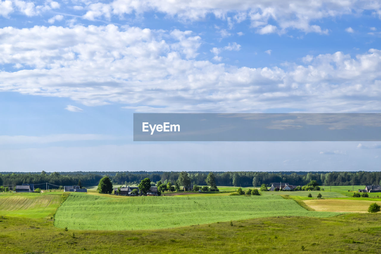 Scenic view of green landscape against cloudy sky