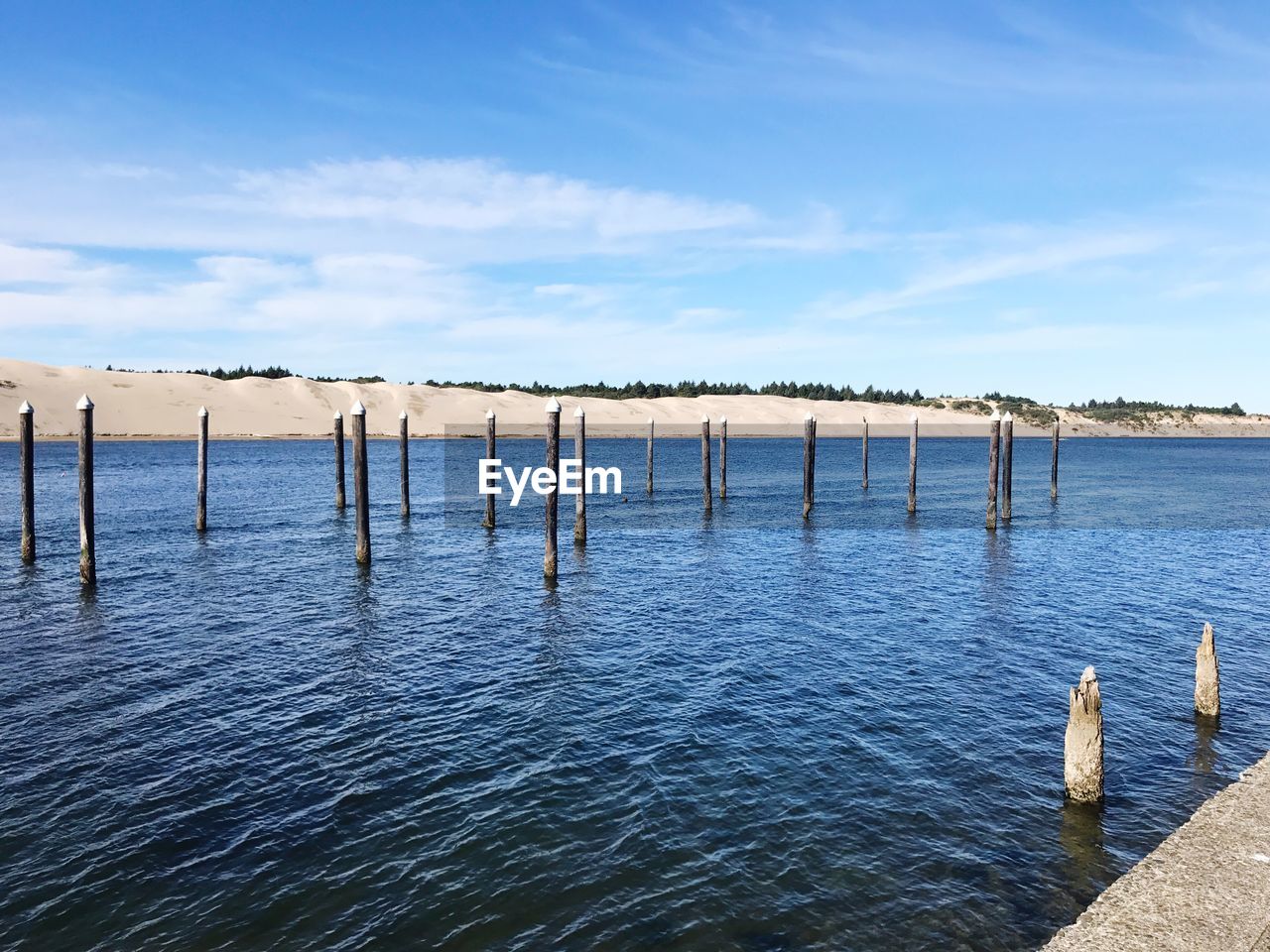 Wooden posts in sea against sky