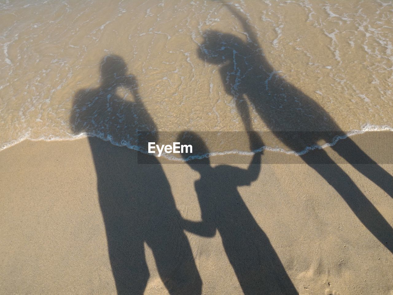 Shadow of family on sand at beach