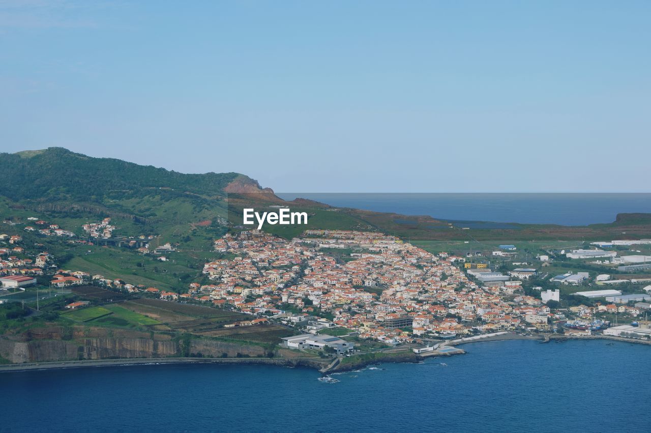 Aerial view of townscape by sea against clear sky