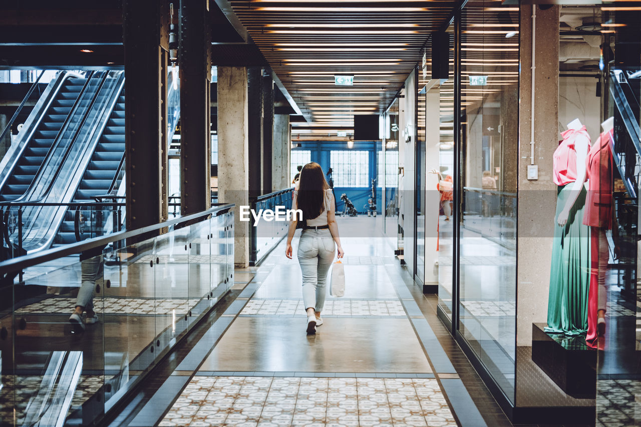 Modern latina young woman walking in large modern mall. young pretty brunette female consumer