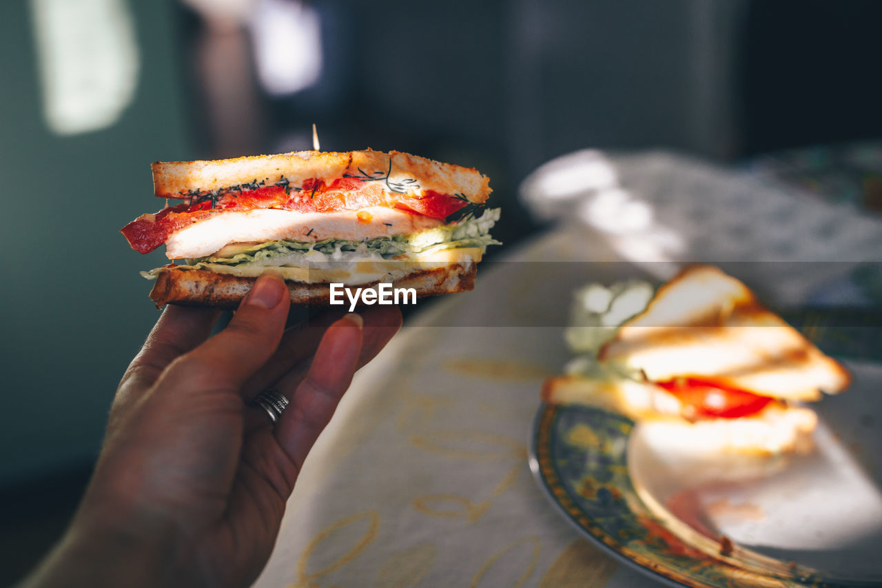 CLOSE-UP OF PERSON HAND HOLDING PIZZA